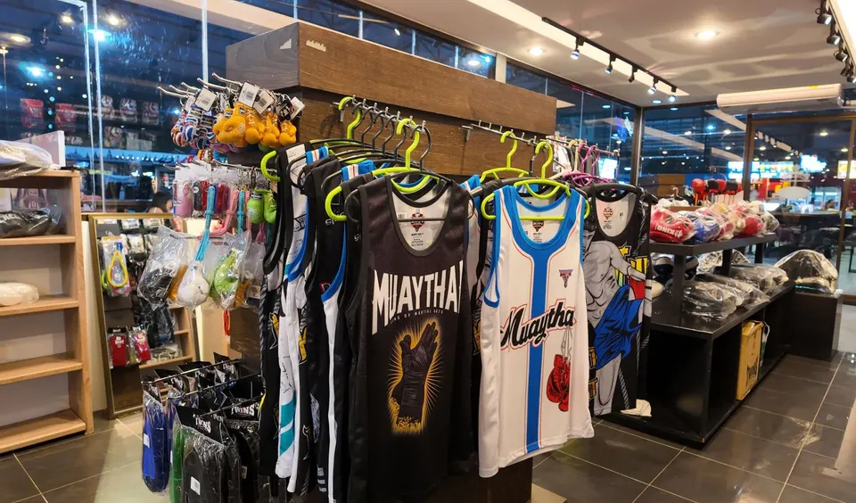 Rack of MUAYTHAI singlets, with mini-glove keyrings and other accessories on the side