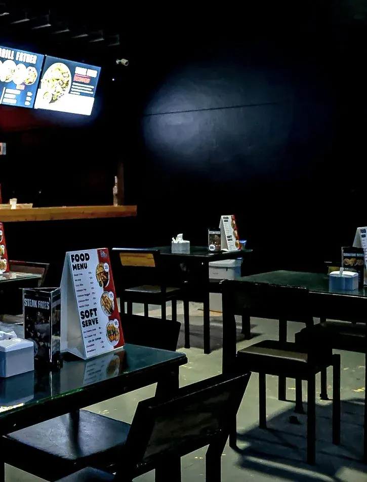Tables with food menu stands in the dining area beside the grill counter