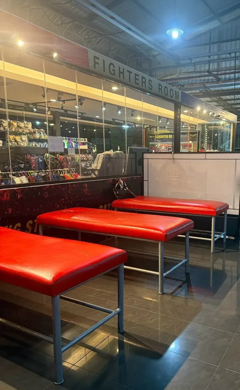 Red massage benches lined up beside the FIGHTERS ROOM sign in the stadium hall