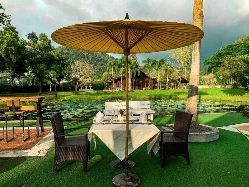 A table for two under a parasol on the lawn, overlooking the lotus pond