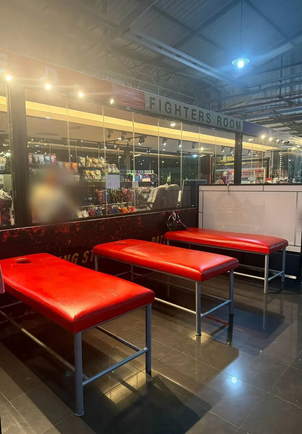 Three red massage benches in front of the glass wall under the FIGHTERS ROOM sign