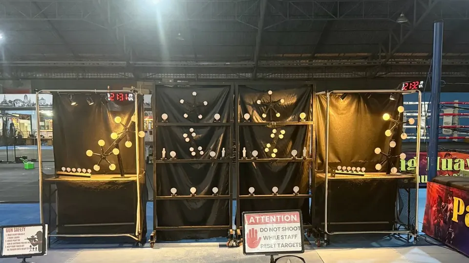 The airsoft shooting lanes: knock-down and spinner targets on black stands, shot timers and a sign asking guests not to shoot while staff reset targets