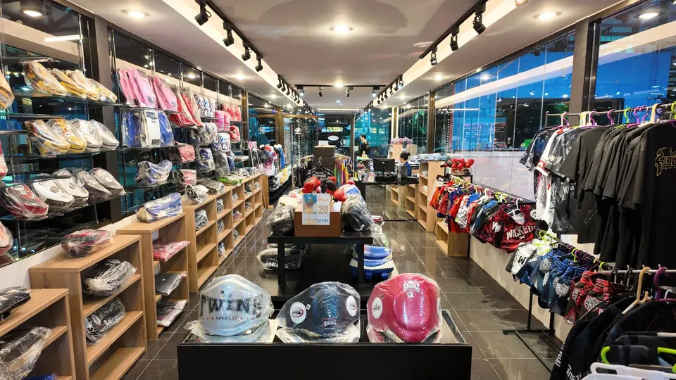 Shop aisle with boxing gloves and pads on the left, Muay Thai shorts on the right and belly pads in the foreground